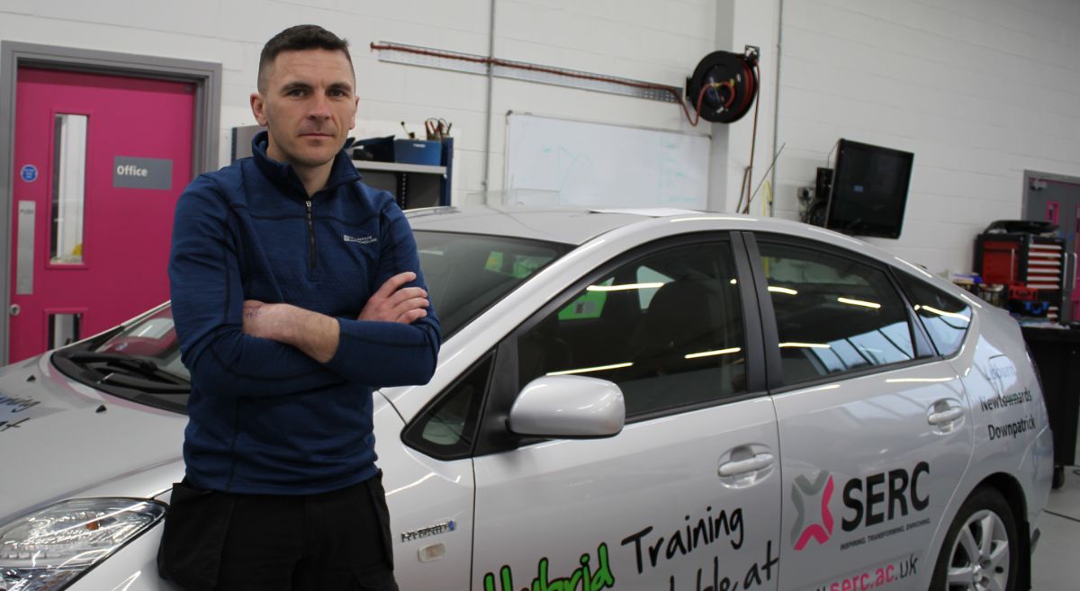 Male student posed infront of Hybrid car